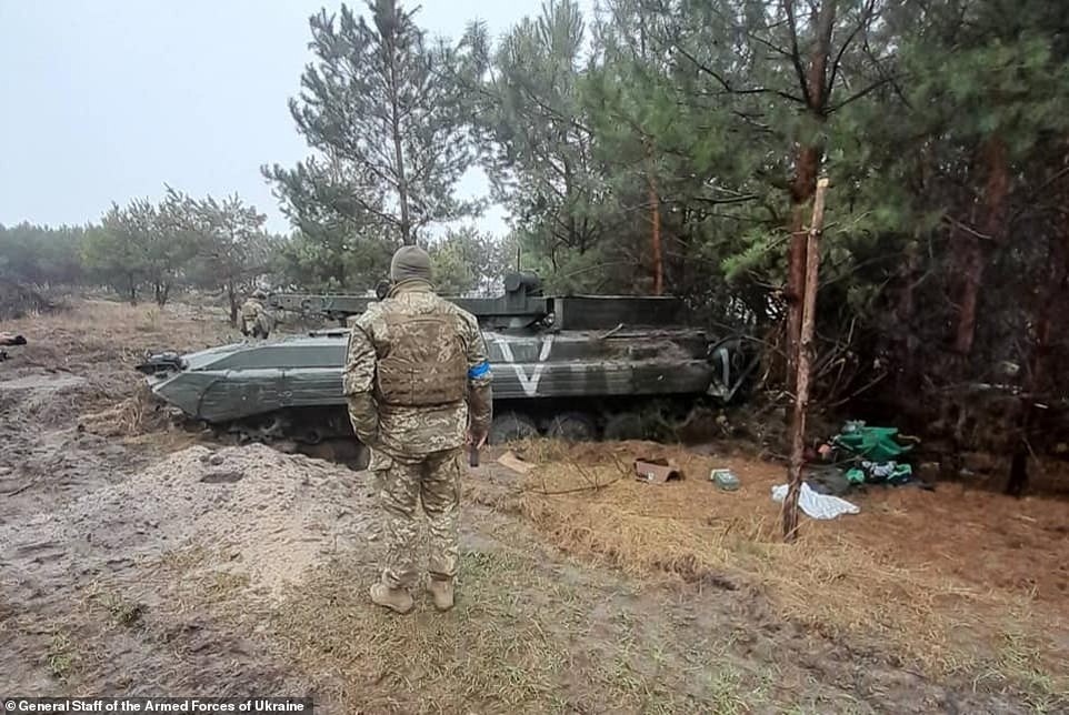 A Ukrainian soldier inspects a damaged Russian tank depicting the 'V' sign as their armed forces continue to share photographs of heavy Russian losses